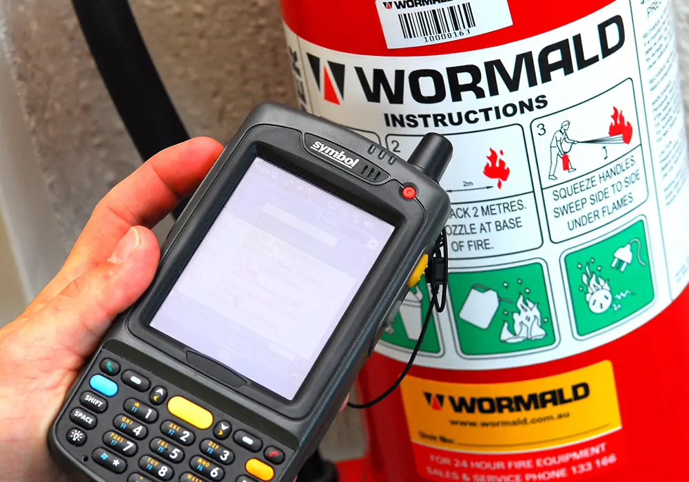 Wormald technician scanning a fire extinguisher service tag