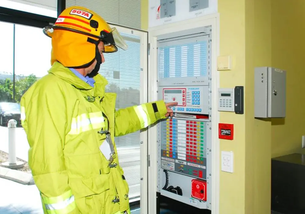 Wormald technician in protective gear at a fire panel